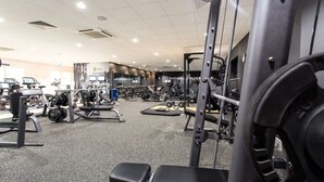 Une salle de sport équipée de divers appareils d’entraînement, notamment des machines à poids et des poids libres.