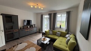 Een moderne woonkamer met een bank, een televisie, een kast en een eethoek.