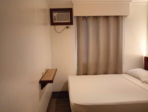 A hotel room with a bed, a bedside table, a wall-mounted air conditioner, and a window with curtains. - Dormitels.ph - El Nido (El Nido)
