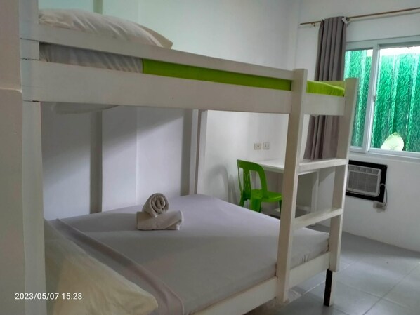 A bunk bed room with a green chair and a window with curtains. - Dormitels.ph - El Nido (El Nido)