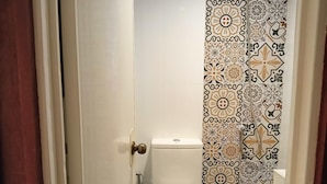 Une salle de bain avec des toilettes, un rideau de douche à motifs floraux et une serviette posée sur la lunette des toilettes.