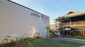 Façade d’un hôtel avec un mur blanc, une pelouse verte et une enseigne publicitaire indiquant « Suites ECO HOTEL » et « POPS District El Nido ».