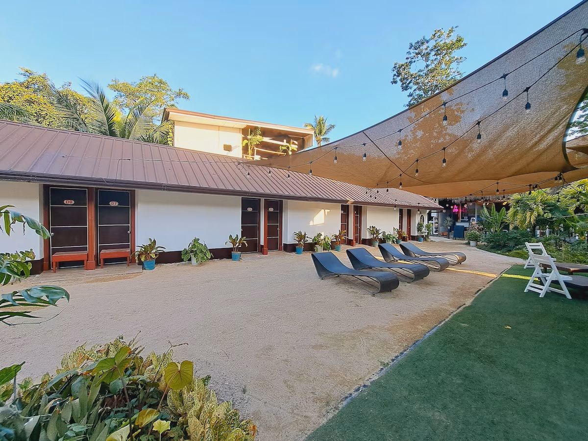 A building with a covered outdoor area, multiple doors, and lounge chairs.