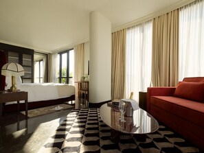 A hotel room with a bed, a red sofa, a coffee table, a lamp, and a window with curtains. - Marly Boutique Hotel (Casablanca)