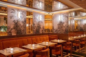 A restaurant with booths and tables, warm lighting, and decorative wall murals. - Marly Boutique Hotel (Casablanca)