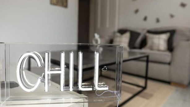 Egy átlátszó akril tábla, melyen a „CHILL” szó szerepel, modern, minimalista belső térben.