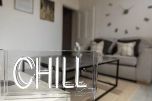 Kirkas akryylikyltti, jossa on sana ”CHILL” kirjoitettuna modernilla, minimalistisella tyylillä, ja se on sijoitettu nykyaikaiseen sisustukseen.