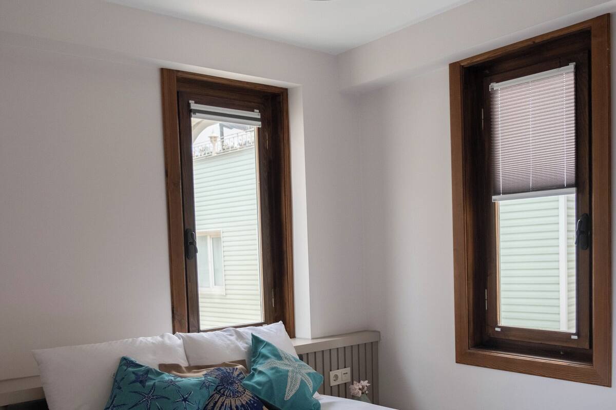 Un dormitorio con una cama grande, dos ventanas y techo de madera.