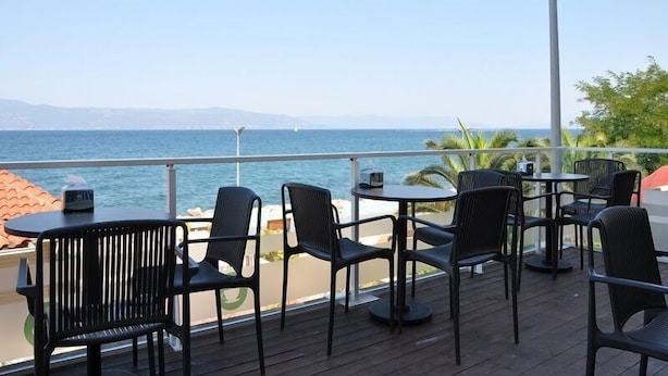 A deck with outdoor seating overlooking a body of water, featuring tables and chairs. - Olimarin Otel (Mudanya)