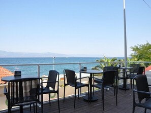 Eine Terrasse mit Sitzgelegenheiten im Freien mit Blick auf ein Gewässer, ausgestattet mit Tischen und Stühlen.