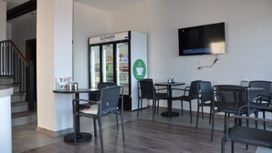 A modern café with a coffee machine, seating area, and a refrigerator labeled 'OLIMARIN'. - Olimarin Otel (Mudanya)