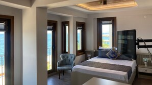 A modern hotel room with a large bed, a seating area, and a TV. - Olimarin Otel (Mudanya)