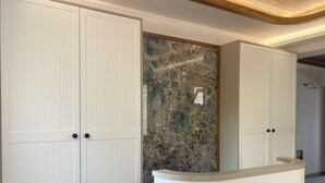 A room with two large white wardrobes, a marble accent wall, and a white reception desk. - Olimarin Otel (Mudanya)