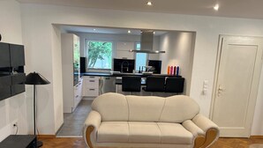 A modern living room with a beige sofa, a coffee table, and a TV stand. - Cozy terraced house for up to 8 people1 minute from the trade fair (Offenburg)