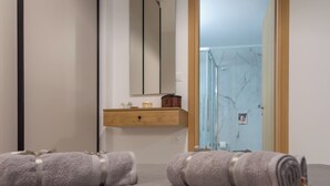 A bathroom with a wooden vanity, a mirror, and towels on the floor. - The Hospitality of the 11 Brothers (kissamos)