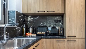 A modern kitchen with a sink, countertop, wooden cabinets, a toaster, and a kettle. - The Hospitality of the 11 Brothers (kissamos)