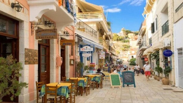 Une rue étroite bordée de terrasses et de divers commerces.