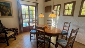 Un comedor con una mesa redonda de madera, seis sillas y lámparas colgantes.