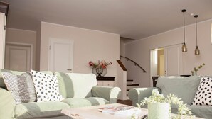 A living room with a light green sofa, a coffee table, and a staircase in the background. - Zum Brandenburger Tor 13 (Damme)