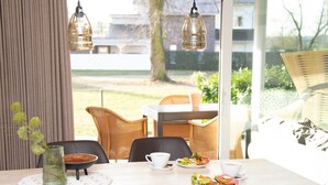 A dining area with a table set for two, chairs, a vase with greenery, and a view of the outdoors. - Zum Brandenburger Tor 13 (Damme)