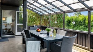 Eine Außenpatio mit überdachter Sitzgruppe, einem Esstisch und Stühlen.