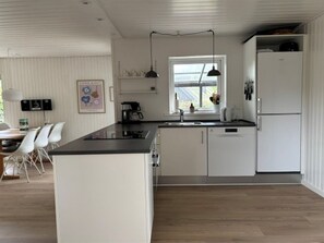 A modern kitchen with white cabinetry, a black countertop, and a window providing natural light. - "Nicklas" - 250m from the sea by Interhome (Sydals)