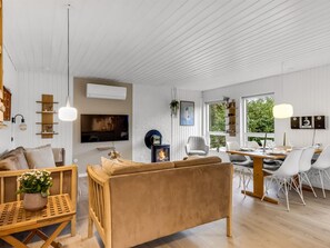 En moderne stue med sofa, TV og spiseområde med stole.
