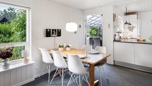 Eine moderne Küche mit weißen Schränken, einem Holztisch und weißen Stühlen.