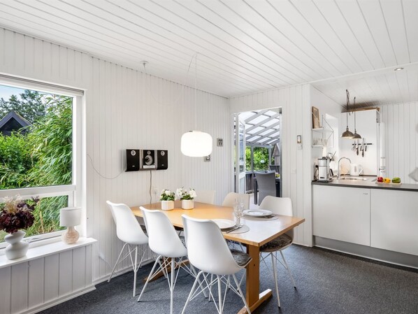 A modern kitchen with white cabinetry, a wooden dining table, and white chairs. - "Nicklas" - 250m from the sea by Interhome (Sydals)