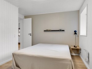 Et soveværelse med en seng, et natbord, en lampe og en radiator.