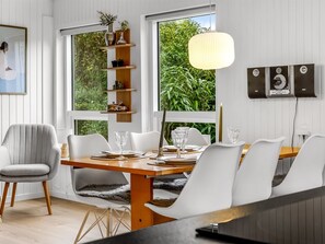 A dining area with a wooden table set for four, white chairs, and a pendant light.