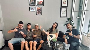 Un grupo de personas sentadas en un sofá y una mesa en una habitación con cuadros en la pared.