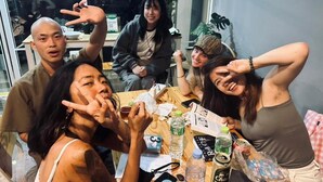 Un grupo de personas sentadas alrededor de una mesa con varios objetos como botellas, un menú y un teléfono.