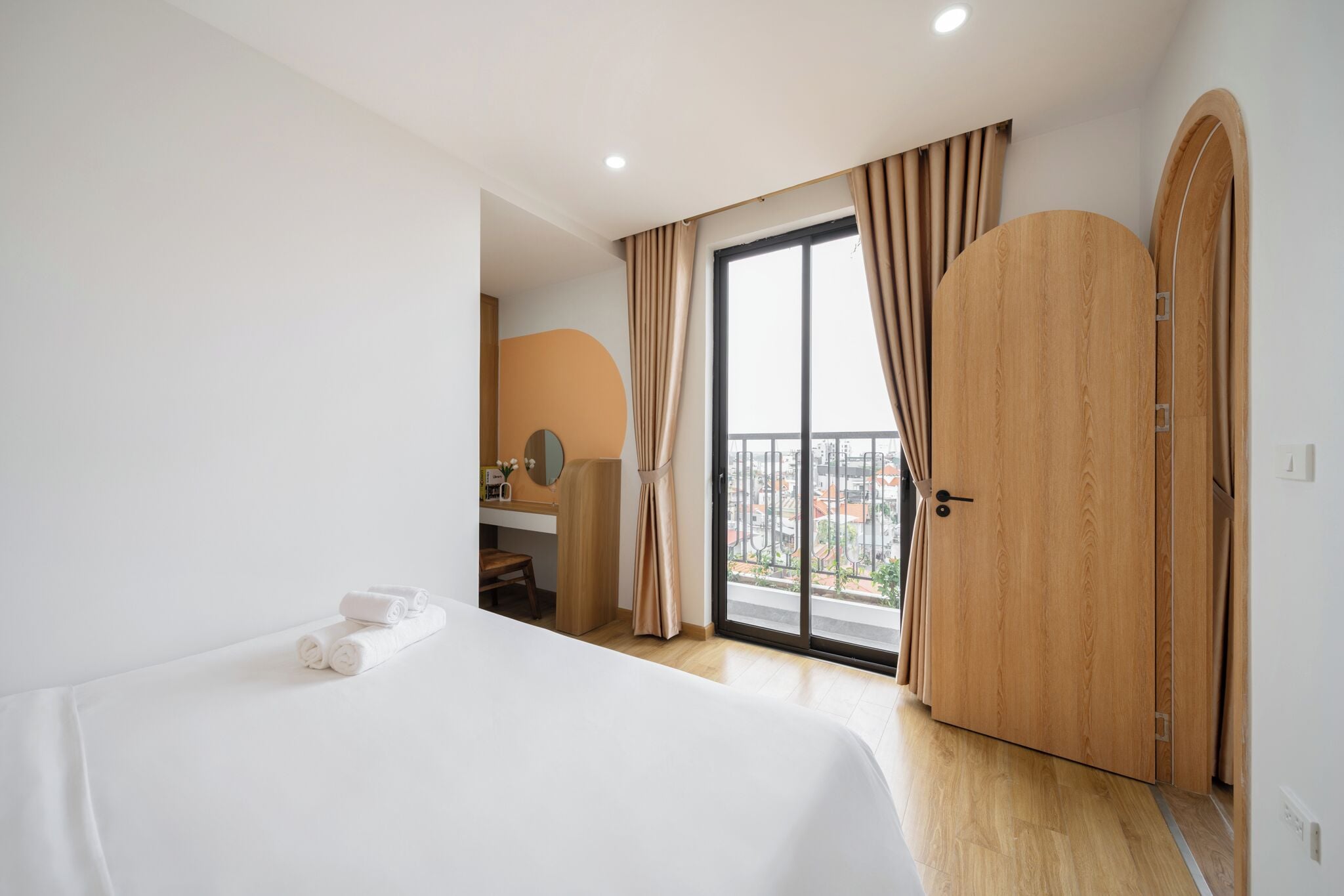 A hotel room with a bed, a bathroom, and a balcony with curtains.