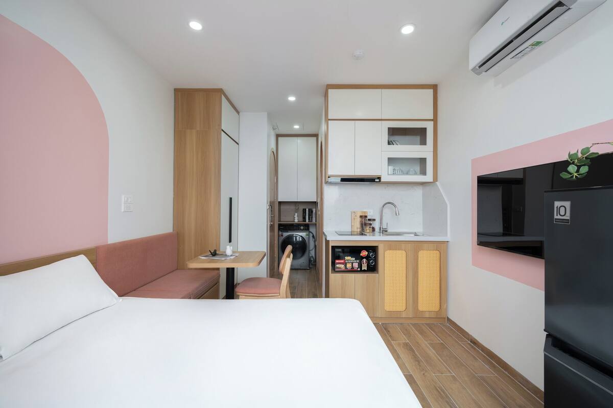Una habitación de hotel compacta con cama, kitchenette, zona de estar y televisión.