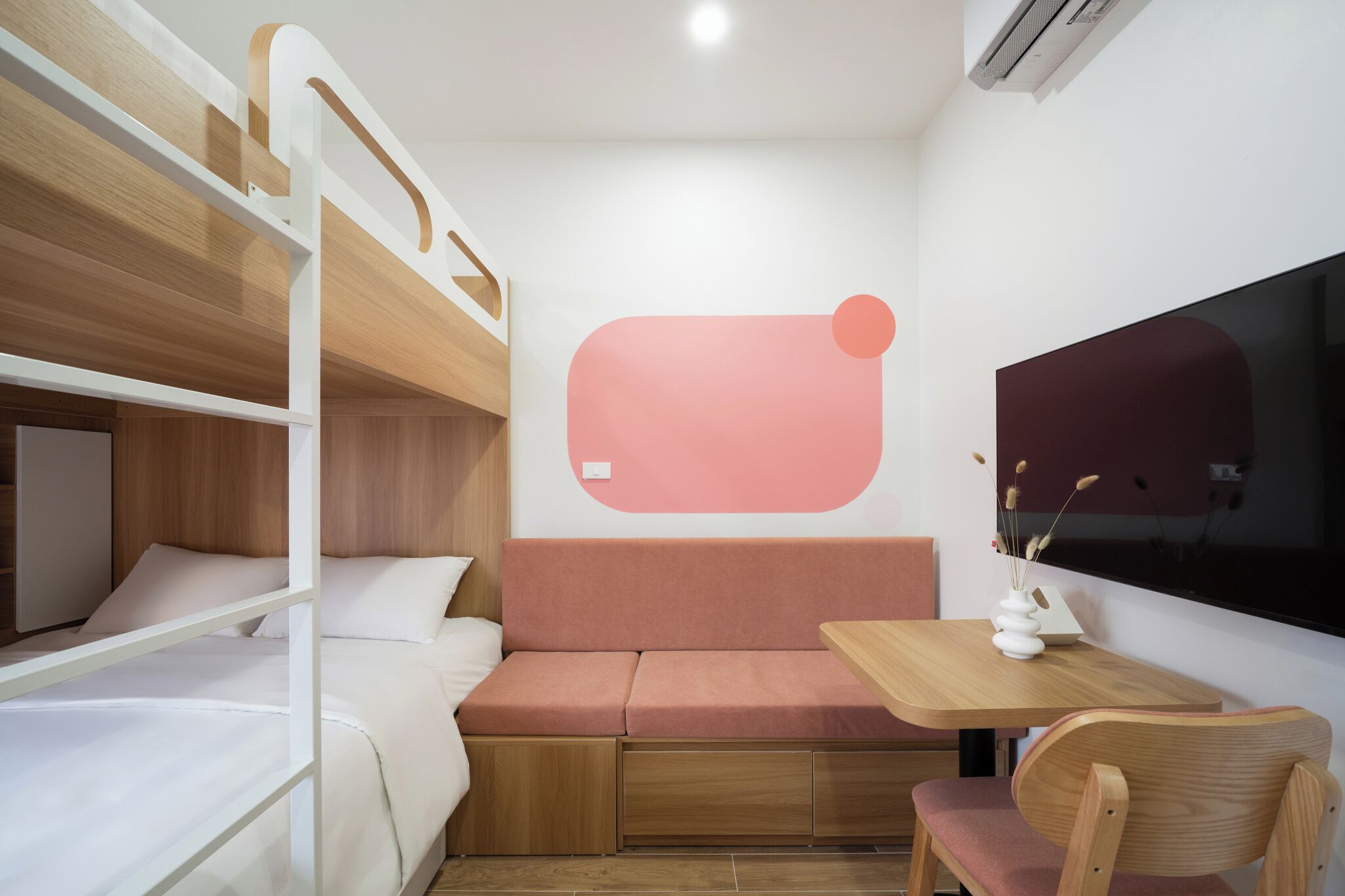 Habitació compacta amb literes, un sofà, una taula petita i un televisor.