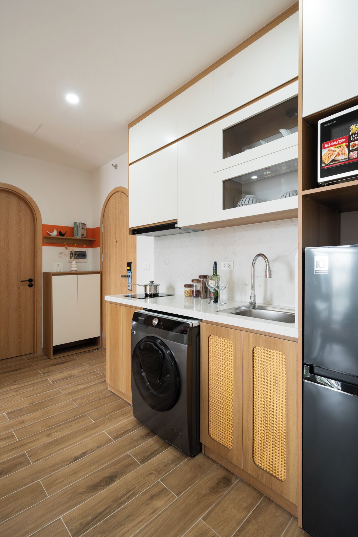 A compact kitchen with a washing machine, a refrigerator, and a sink.