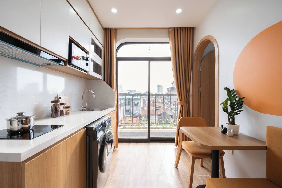 Una cocina moderna con horno empotrado, un lavamanos y una ventana con cortinas.