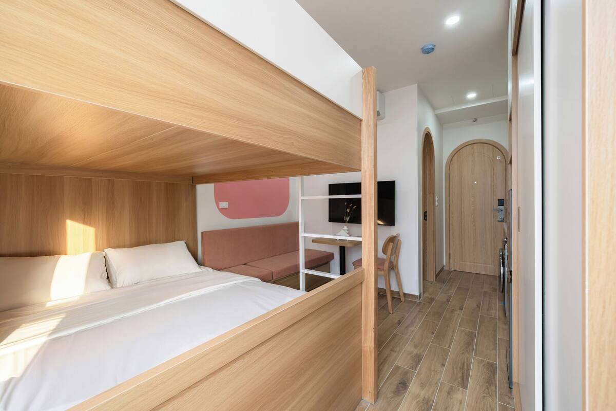 Un dormitorio moderno con una litera, un escritorio y una televisión.