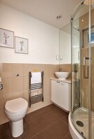 Un baño moderno con inodoro, lavabo y cabina de ducha de vidrio.