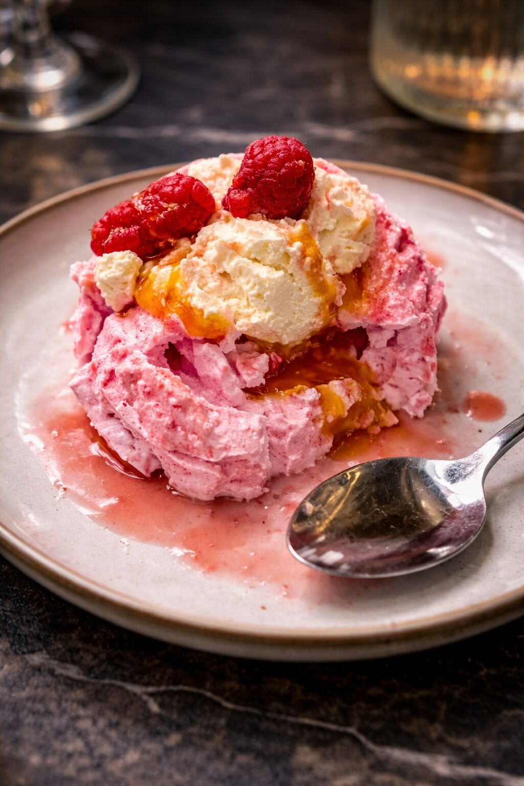 A dessert with raspberries and ice cream on a plate.