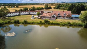 A large estate with multiple buildings, a pond, and surrounding fields.