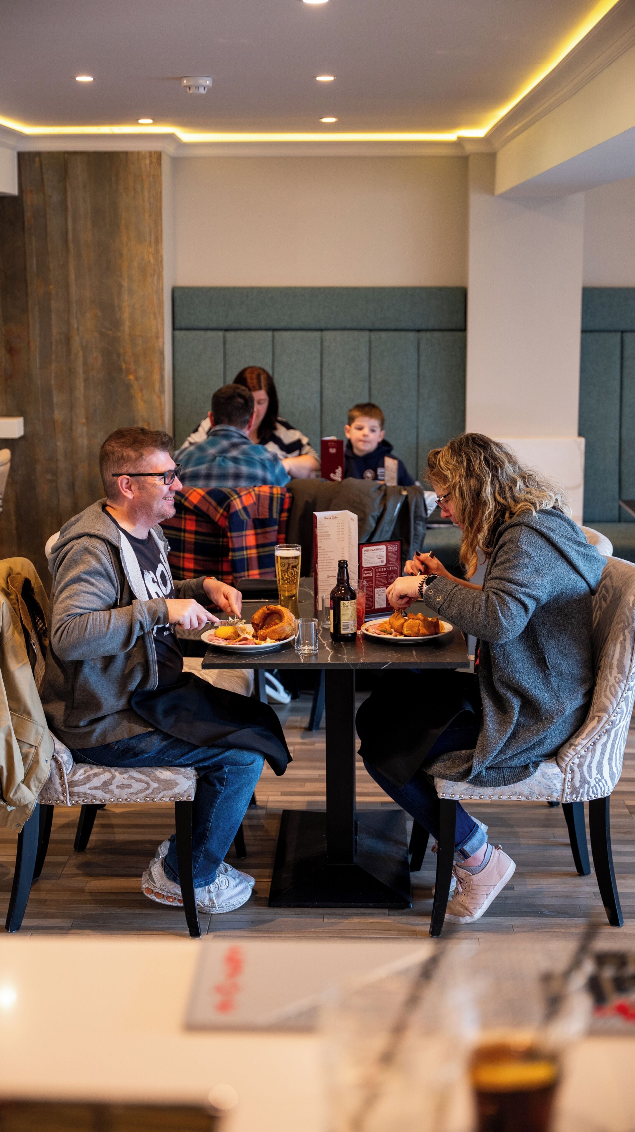 Un comedor con una mesa dispuesta para cuatro personas, un menú y una bebida.