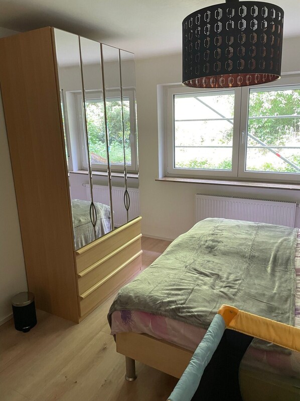 A bedroom with a bed, a wardrobe, a window, and a radiator.
