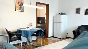 A compact living space with a dining area, kitchenette, and a bed.