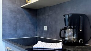 A modern kitchen with a black stovetop, a coffee maker, and a stainless steel oven.