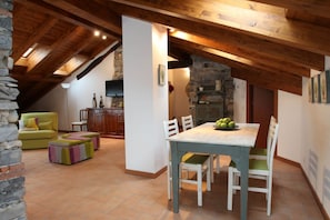 Zona pranzo in soffitta con tavolo e sedie, un divano e un camino in pietra.