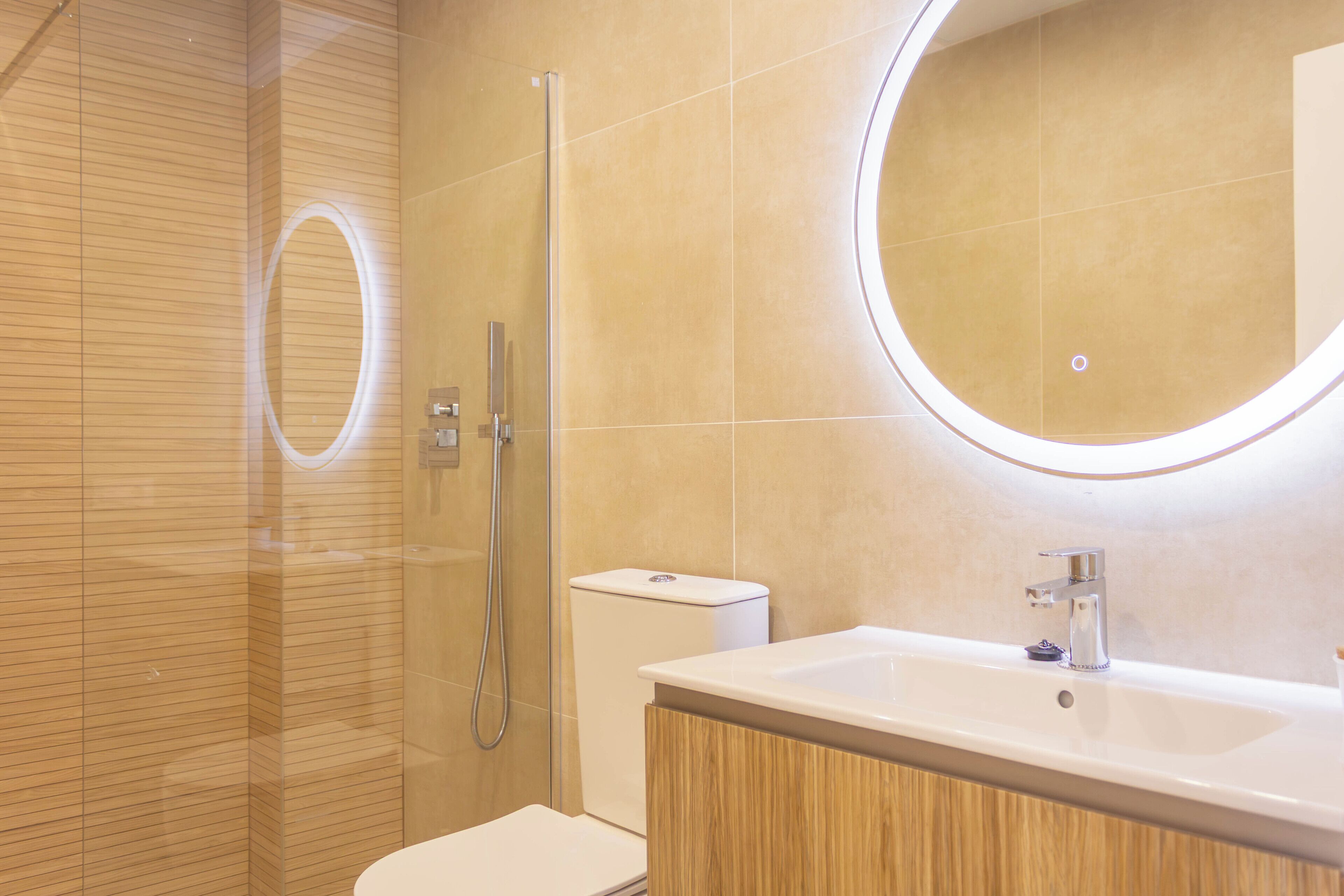 Un bany modern amb una cabina de dutxa de vidre, un vàter i un lavabo amb mirall.