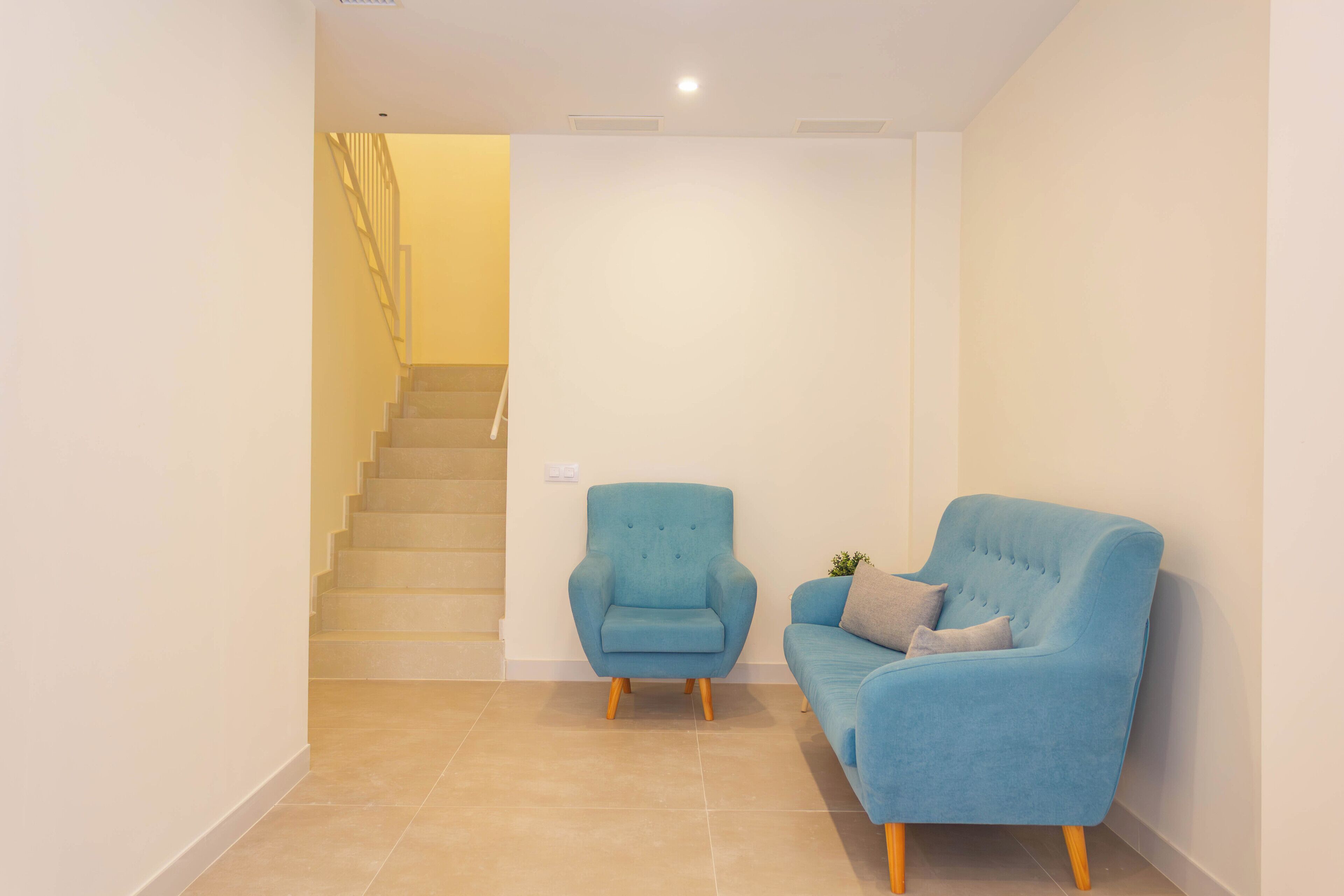 Un interior moderno con una escalera, un sillón azul y un sofá azul.