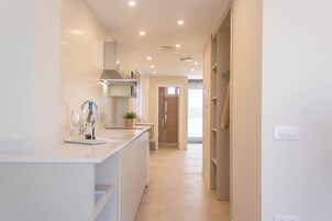Una cocina moderna con una isla central, horno empotrado y vista hacia la zona de estar contigua.